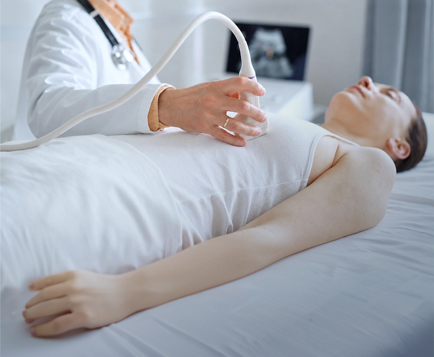 Doctor performing a breast ultrasound scan on a patient in a medical clinic.