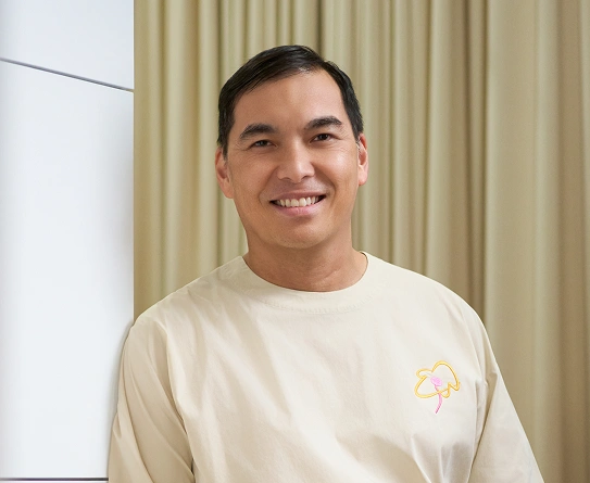 Portrait of Dr. Evan Woo, consultant plastic and breast surgeon in Singapore smiling in his clinic.