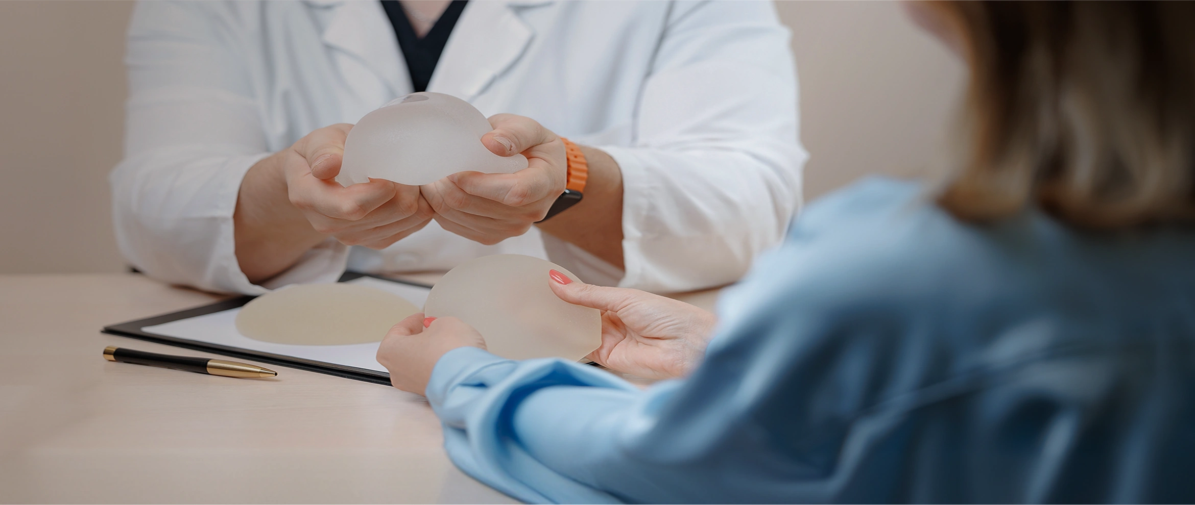 Dr Evan Woo holding silicone breast implants during a consultation with a patient in Singapore