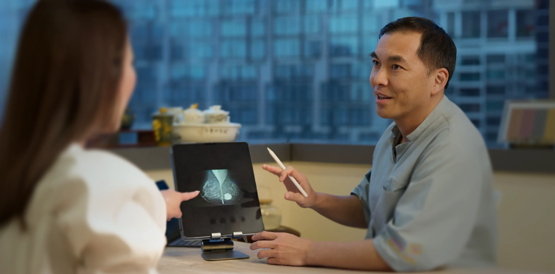 Doctor reviewing a mammogram scan on a digital tablet with a patient during a consultation