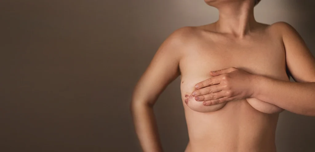 Woman covering her hands over her chest with a brown background.
