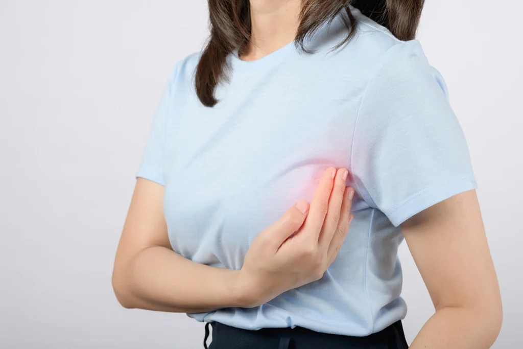 Woman touching her breast indicating chest pain or examination.