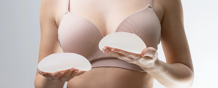 A woman holding silicone implants to demonstrate options for reconstructive breast surgery after cancer treatment.