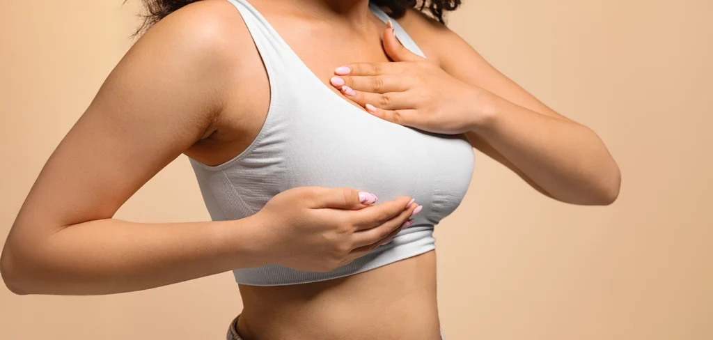 Woman performing a self-examination while wearing a sports bra.