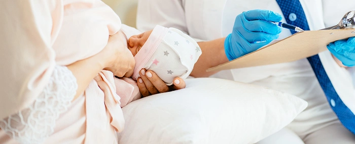 A healthcare practitioner providing a clinical assessment and care support for a breastfeeding mother.