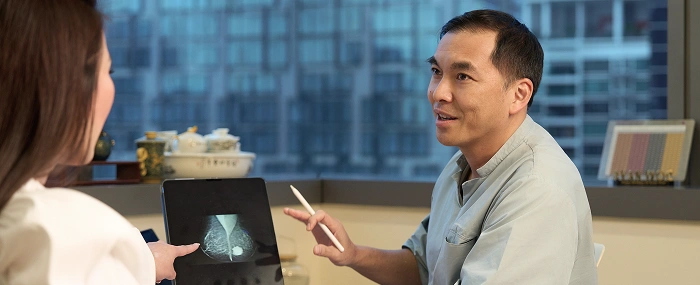 Dr Evan Woo conducting a breast screening and assessment consultation with a patient in a clinic.