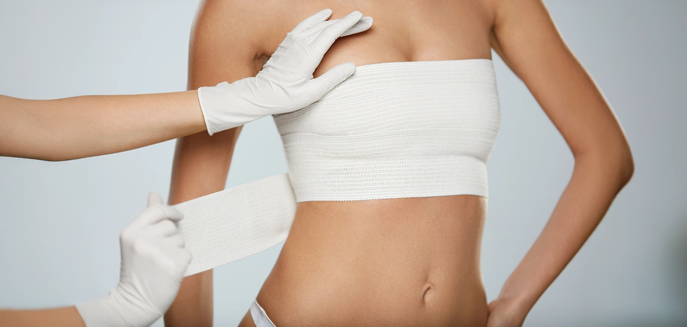 Medical professional wrapping a woman's torso in white bandages.