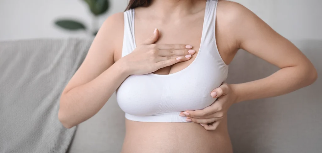 Woman holding her chest while wearing a white sports bra.