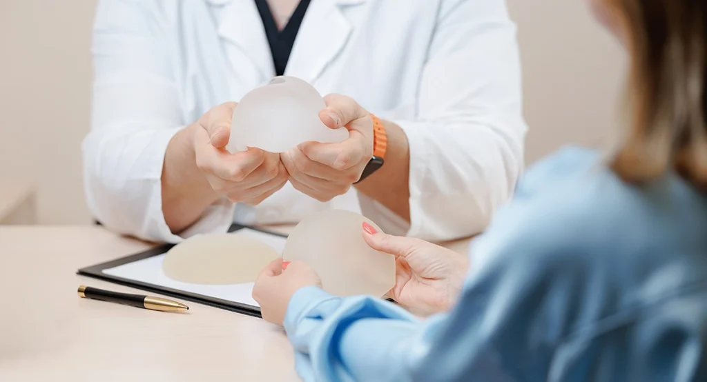 Doctor and patient holding silicone breast implants during a consultation.